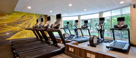 A gym with multiple treadmills and exercise bikes, large windows, and a modern design.