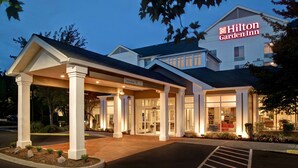 Een Hilton Garden Inn met overdekte entree, duidelijke bewegwijzering en een parkeerplaats.