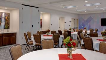 A conference room with round tables, chairs, and floral centerpieces.