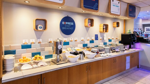 Zona de desayuno tipo buffet con diferentes opciones de comida y una estación de café.