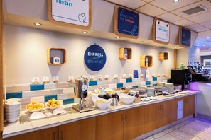 Zona de desayuno tipo buffet con diferentes opciones de comida y una estación de café.