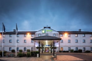 A Holiday Inn Express building with a covered entrance and a flagpole.