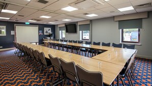 Un salón de conferencias con una larga mesa, sillas, una pantalla de proyector y un amplio ventanal.