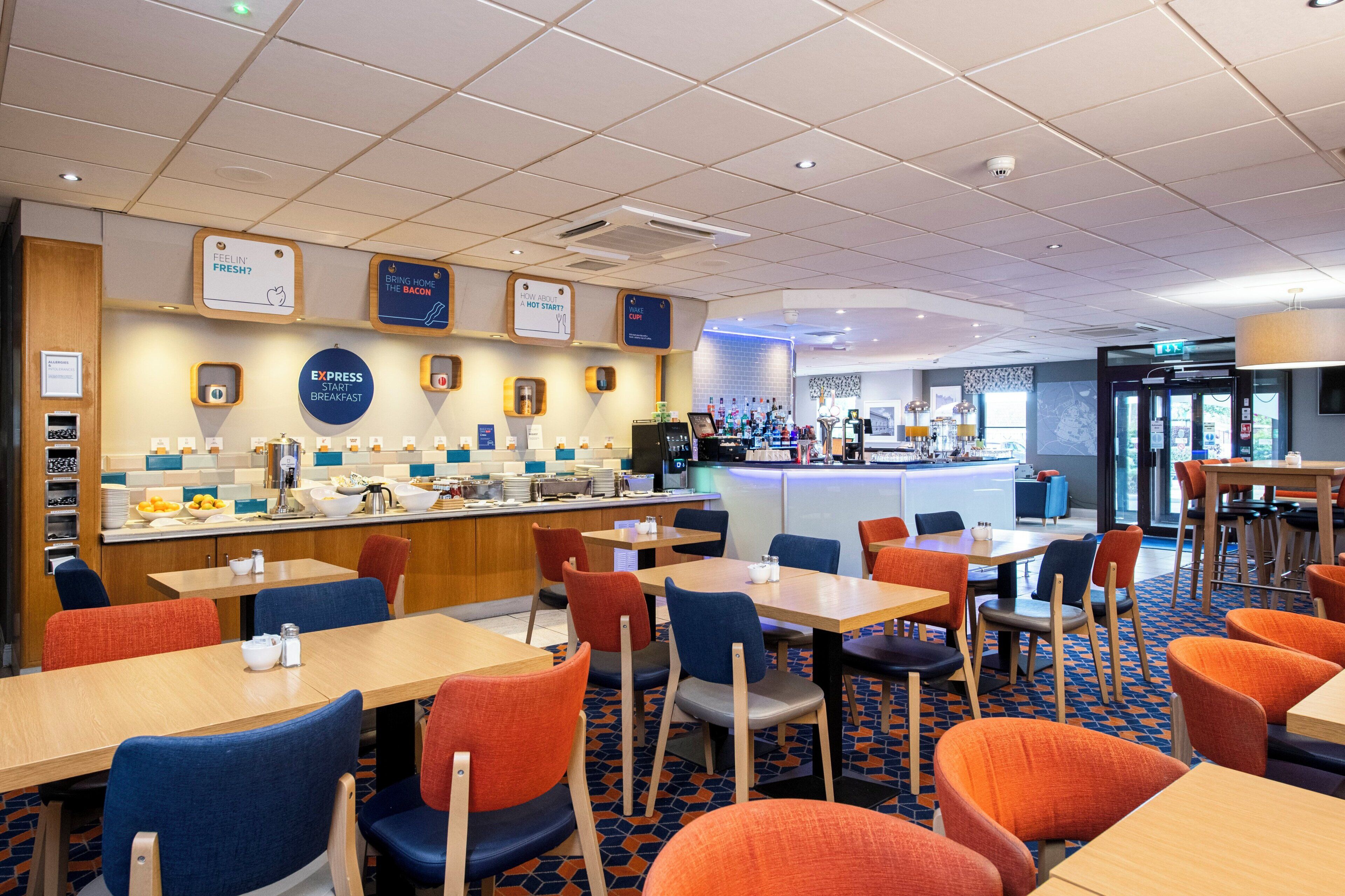 Un restaurant d’hôtel proposant un buffet de petit-déjeuner, un espace repas et une vue sur la ville.