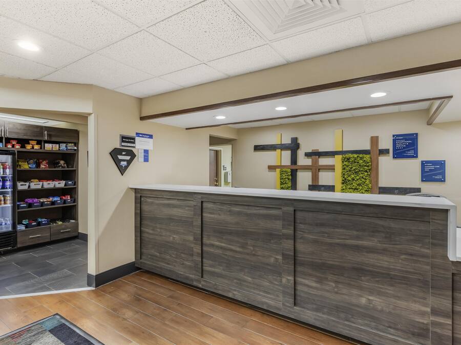 Un área de recepción con mostrador, un refrigerador lleno de bebidas y una pared con varios letreros.