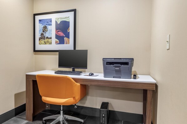 Un bureau moderne, équipé d’un ordinateur, d’une imprimante et d’une chaise orange.