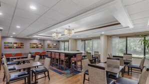 A modern dining area with wooden tables and chairs, a central bar, and colorful wall art. - Best Western Plus Lexington Inn (Lexington)