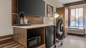 A modern hotel room with a flat-screen TV, a desk with a coffee maker, a microwave, a mini fridge, a chair, and a large window with curtains. - Best Western Plus Lexington Inn (Lexington)