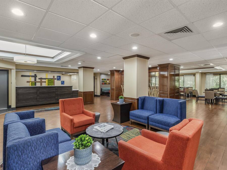 A spacious lobby with seating areas, a reception desk, and a view of the outside through large windows.