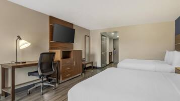 Ein Hotelzimmer mit Bett, Schreibtisch, Stuhl, Fernseher, Kleiderschrank und Spiegel.