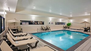 A swimming pool area with lounge chairs and umbrellas, a tiled floor, and a ceiling with recessed lighting. - Hampton Inn North Sioux City (North Sioux City)
