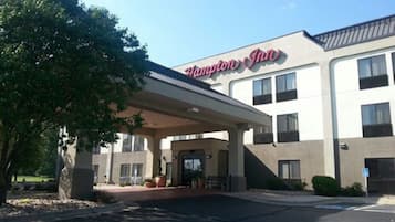 A Hampton Inn hotel with a covered entrance, multiple windows, and a parking lot.