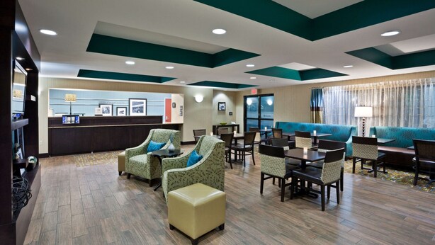 A hotel lobby with a reception desk, seating area, and a view of the outside. - Hampton Inn North Sioux City (North Sioux City)