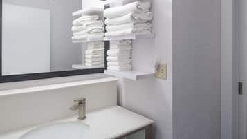 Un baño moderno con un lavamanos blanco, un espejo grande y dos toalleros con toallas dobladas con cuidado.