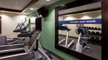 Un gimnasio con cintas de correr, un espejo grande y una frase motivadora.