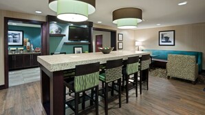 A modern kitchen with a central island, bar stools, and pendant lighting. - Hampton Inn North Sioux City (North Sioux City)