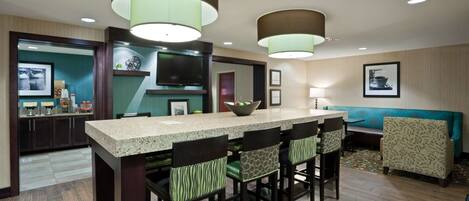 A modern kitchen with a central island, bar stools, and pendant lighting.