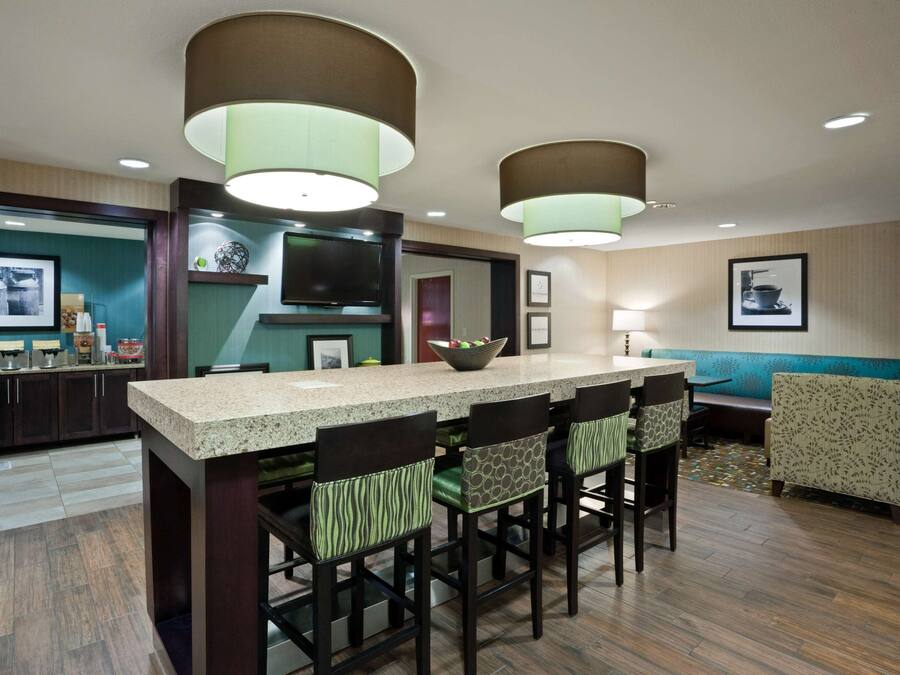 A modern kitchen with a central island, bar stools, and pendant lighting.