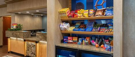 Una estación de autoservicio con aperitivos y bebidas, que incluye variedad de bocadillos, papas fritas y refrescos.