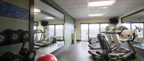 Een sportschool met loopbanden, elliptische trainers en losse gewichten.