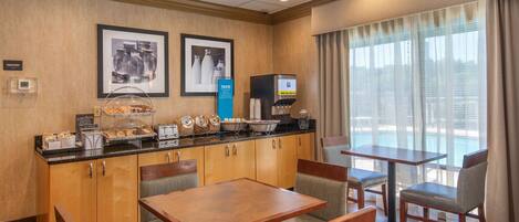 Een hotelkamer met kitchenette, ontbijtbalk en uitzicht op het zwembad.