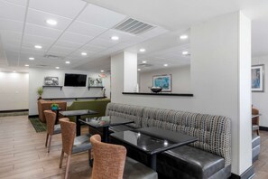 A modern interior with a seating area featuring a patterned sofa and a dining table with chairs. - Comfort Inn Sherman - Denison Area (Sherman)