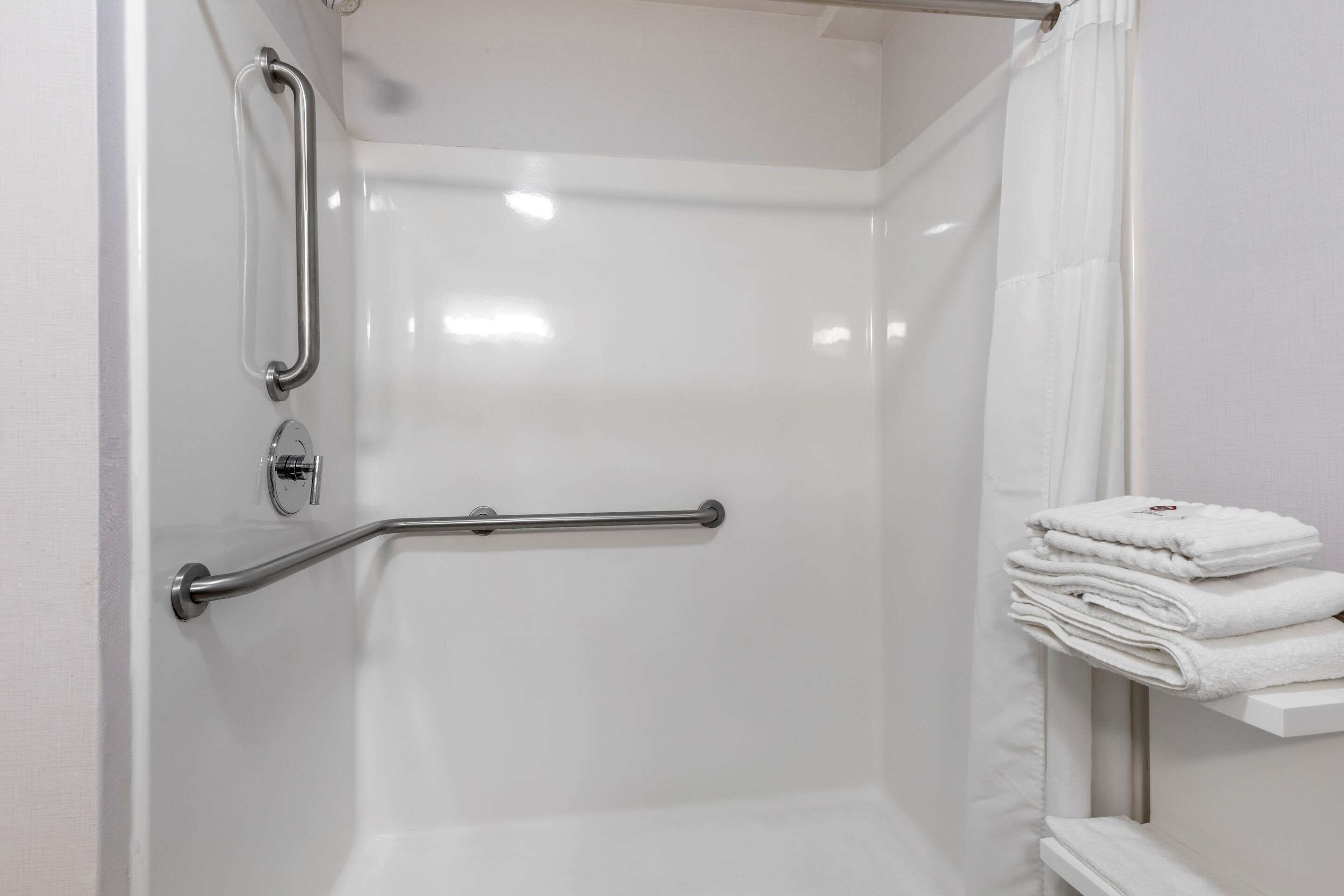 A white shower with a grab bar and a towel rack.