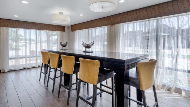 A modern dining area with a black table, yellow chairs, and decorative wall sconces.