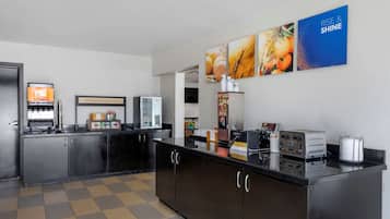 A modern kitchen with stainless steel appliances, a coffee machine, and a toaster. There are wall-mounted pictures and a sign that says "HAPPY BOWL & STARTS HERE".