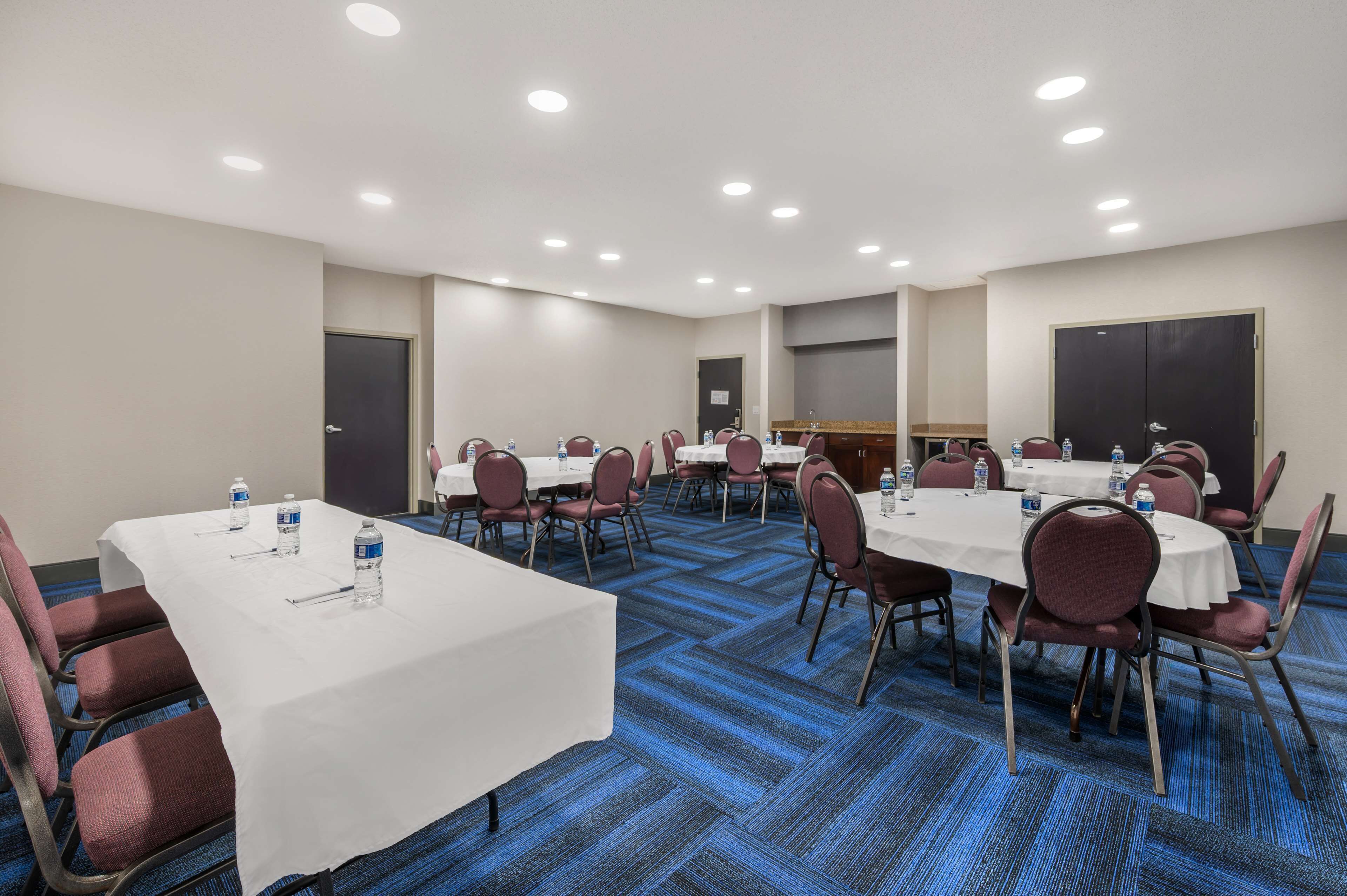 A conference room with multiple tables and chairs, equipped with water bottles and nameplates.