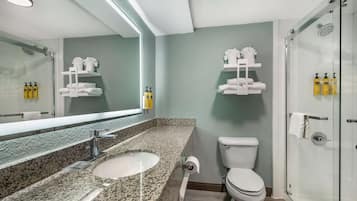 Een moderne badkamer met een wastafel van graniet, witte sanitair en een douchecabine met glazen wanden.