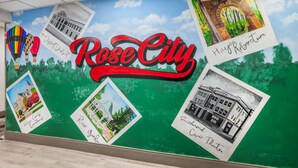 En väggmålning med texten ”Rose City” tydligt framträdande, omgiven av olika illustrerade landmärken och sevärdheter.