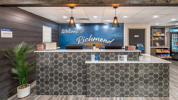 En receptionsdisk med en skylt som säger ”Välkommen till Richmond”, en växt och en liten servering i bakgrunden.