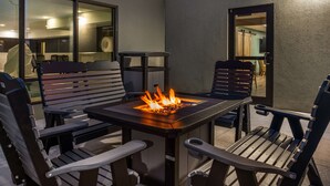 En uteplats med en öppen spis, sittplatser och utsikt in i huset.
