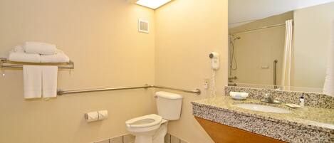A bathroom with a toilet, hand dryer, and a sink with a mirror above it.