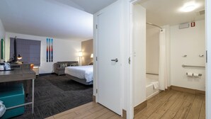 A hotel room with a bed, desk, lamp, and a shower area. - Hampton Inn St. Augustine-I-95 (St. Augustine)
