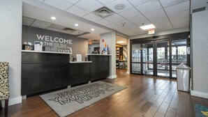 A reception area with a welcome sign, a reception desk, a patterned rug, and a glass door entrance. - Hampton Inn St. Augustine-I-95 (St. Augustine)