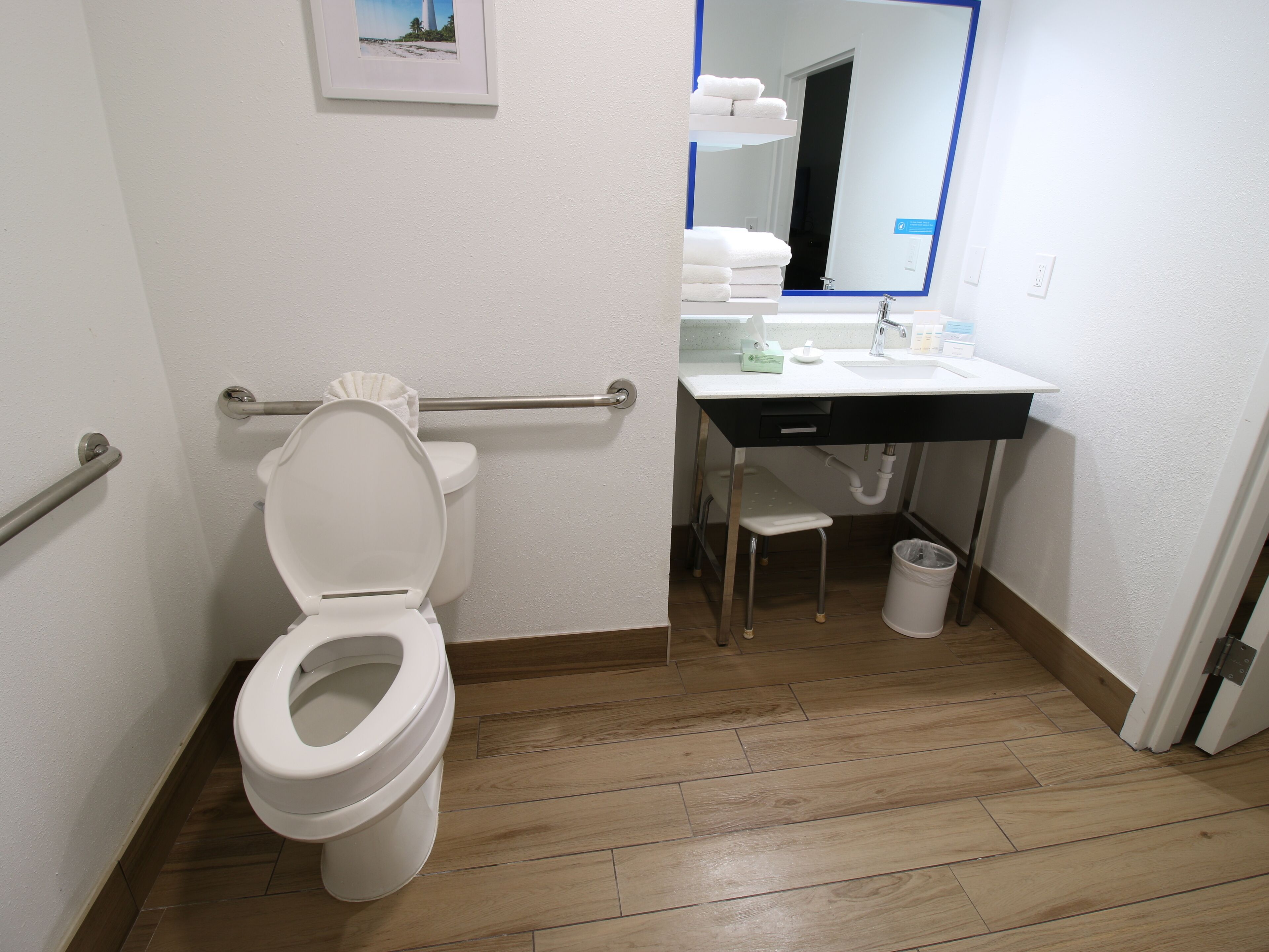 A bathroom with a toilet, a sink, a mirror, and a trash can.