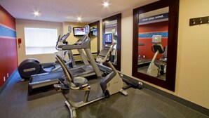 Un gimnasio con cintas de correr, una bicicleta estática y una máquina de remo.