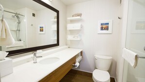 Un baño moderno con lavamanos blanco, un espejo, inodoro y zona de ducha.