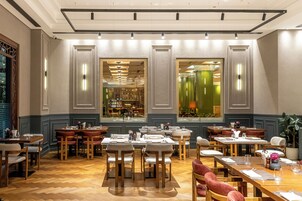 Een restaurant met meerdere eettafels en stoelen, grote ramen met uitzicht op het interieur, en een houten vloer.