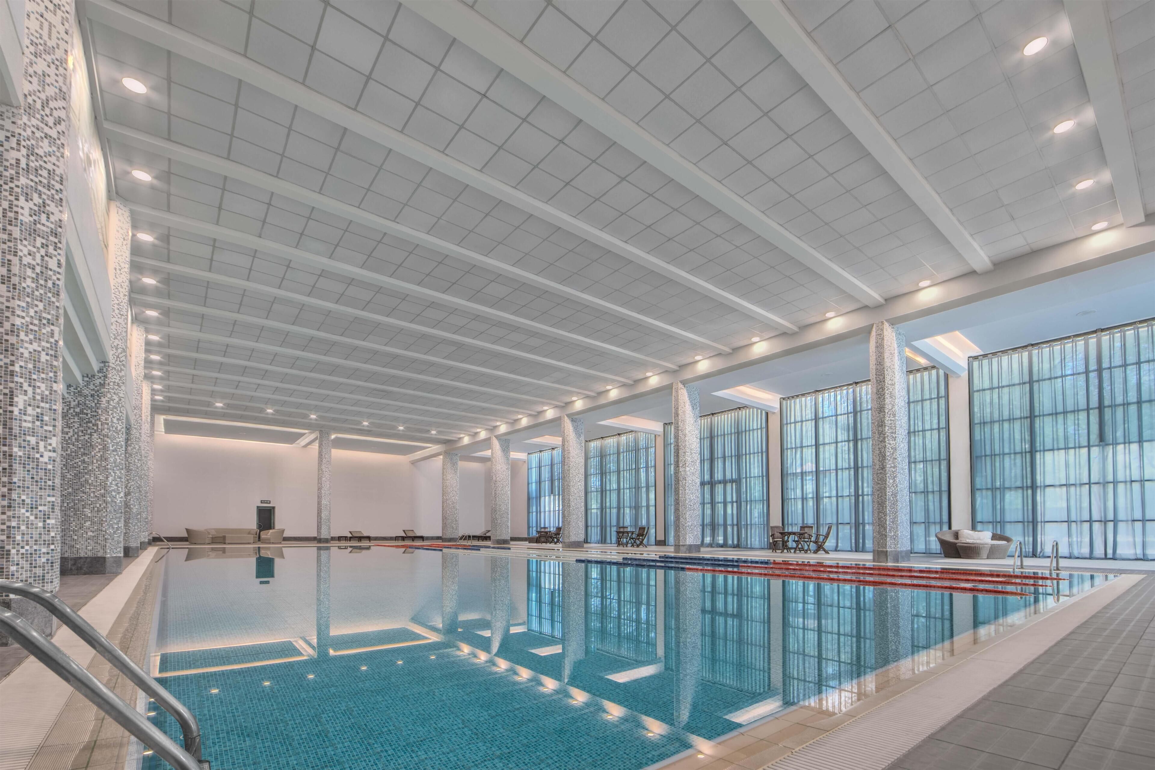 Ein großes Hallenbad mit klarem Wasser, umgeben von großen Fenstern und moderner Architektur.