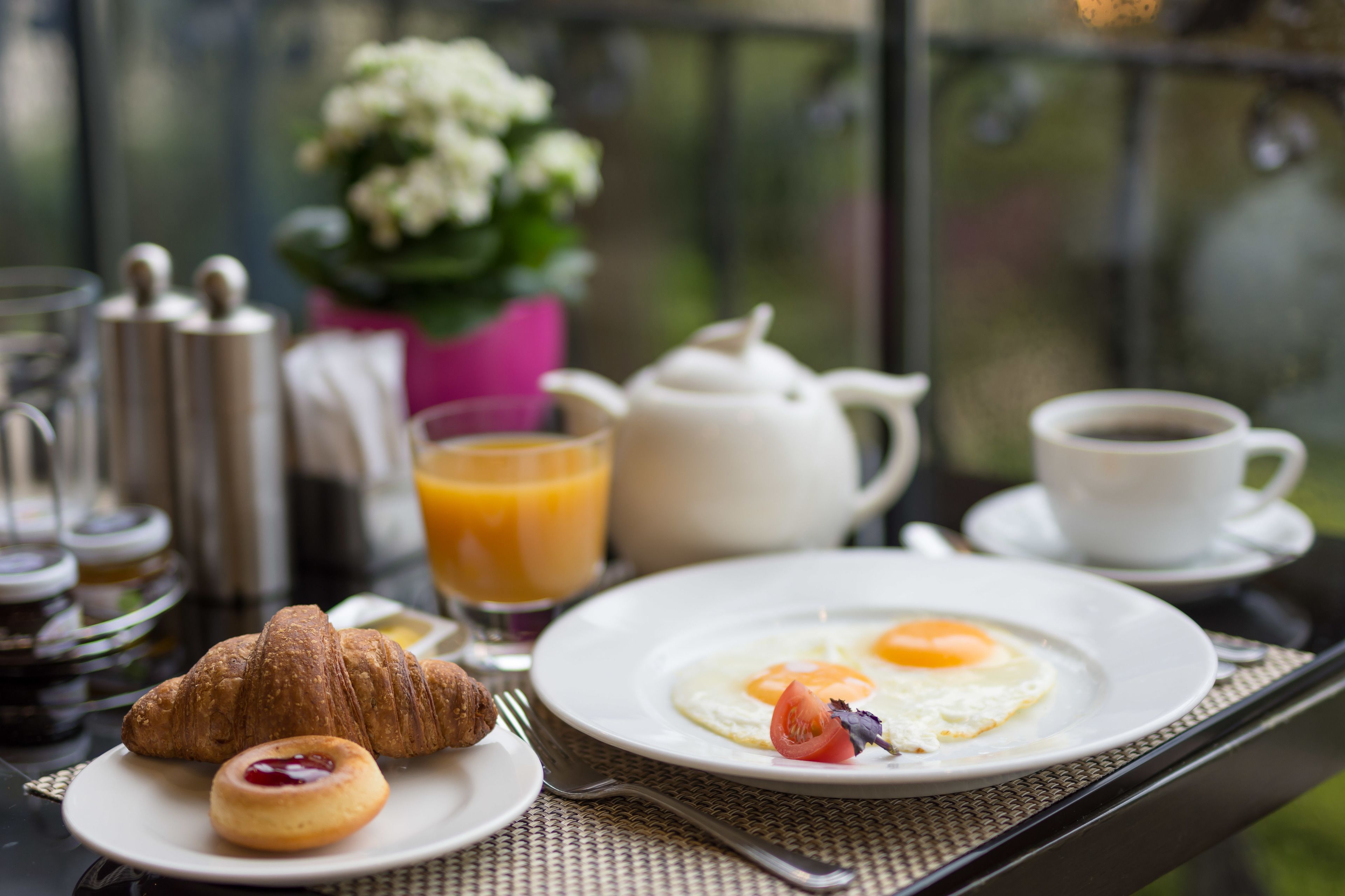 A breakfast table with croissants, eggs, and juice.
