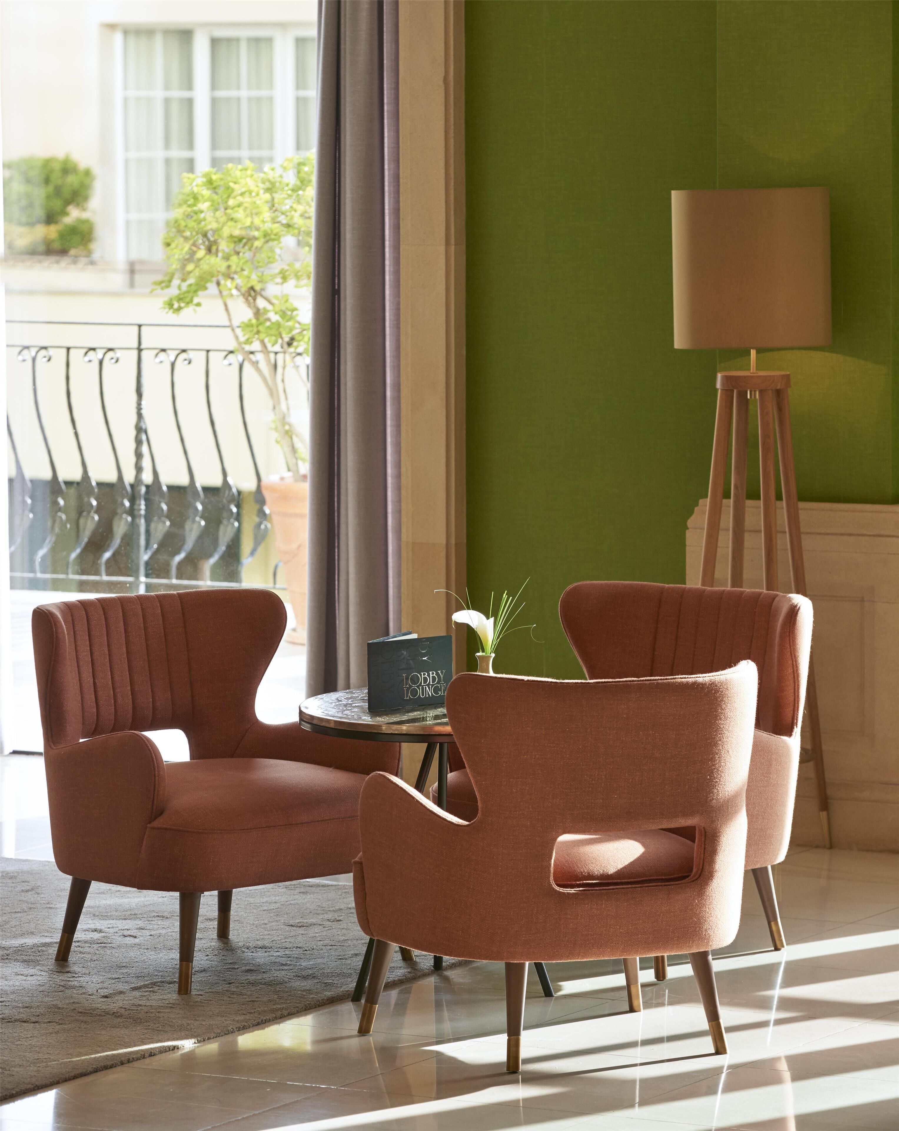 A room with two armchairs, a small table, a floor lamp, and a view of the outdoors.