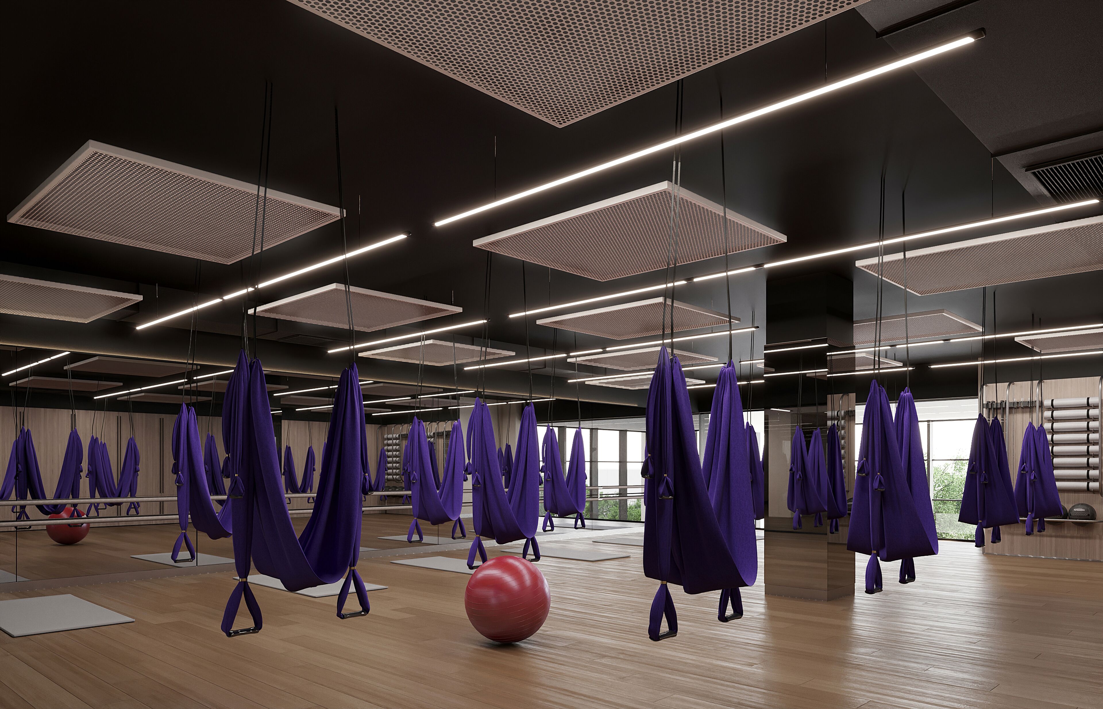 A spacious studio with multiple aerial yoga hammocks, wooden floors, and large windows allowing natural light.
