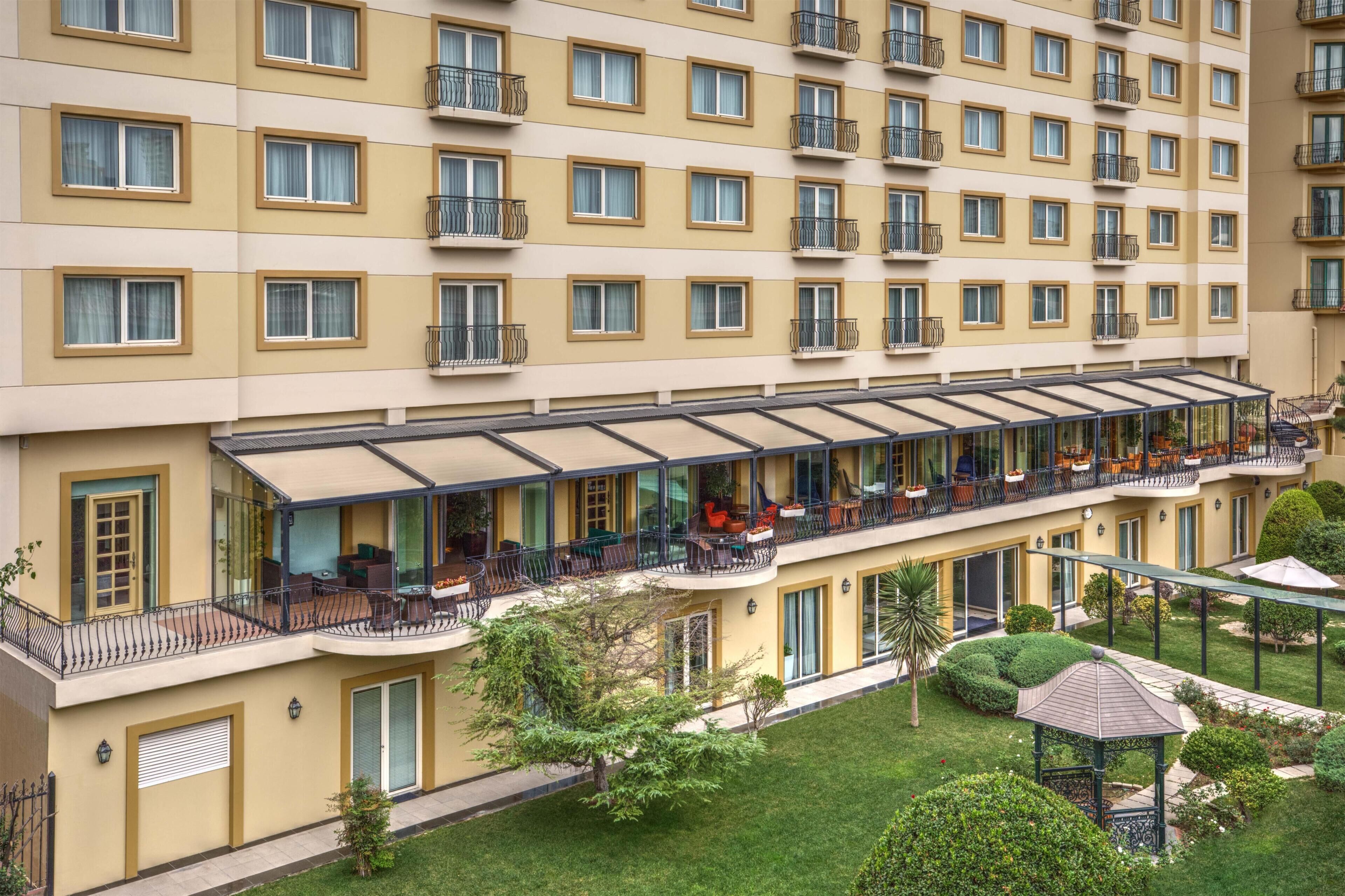 Ein mehrstöckiges Hotel mit Balkonen, Außenbereich und einem gepflegten Garten.