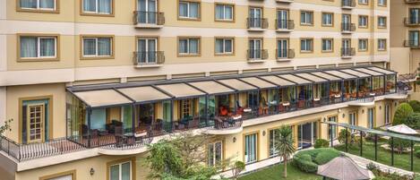 A multi-story hotel with balconies, outdoor seating, and a well-maintained garden.