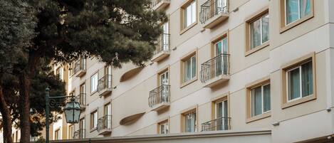 Un hotel de varios pisos con balcones, una entrada cubierta y un césped bien cuidado.