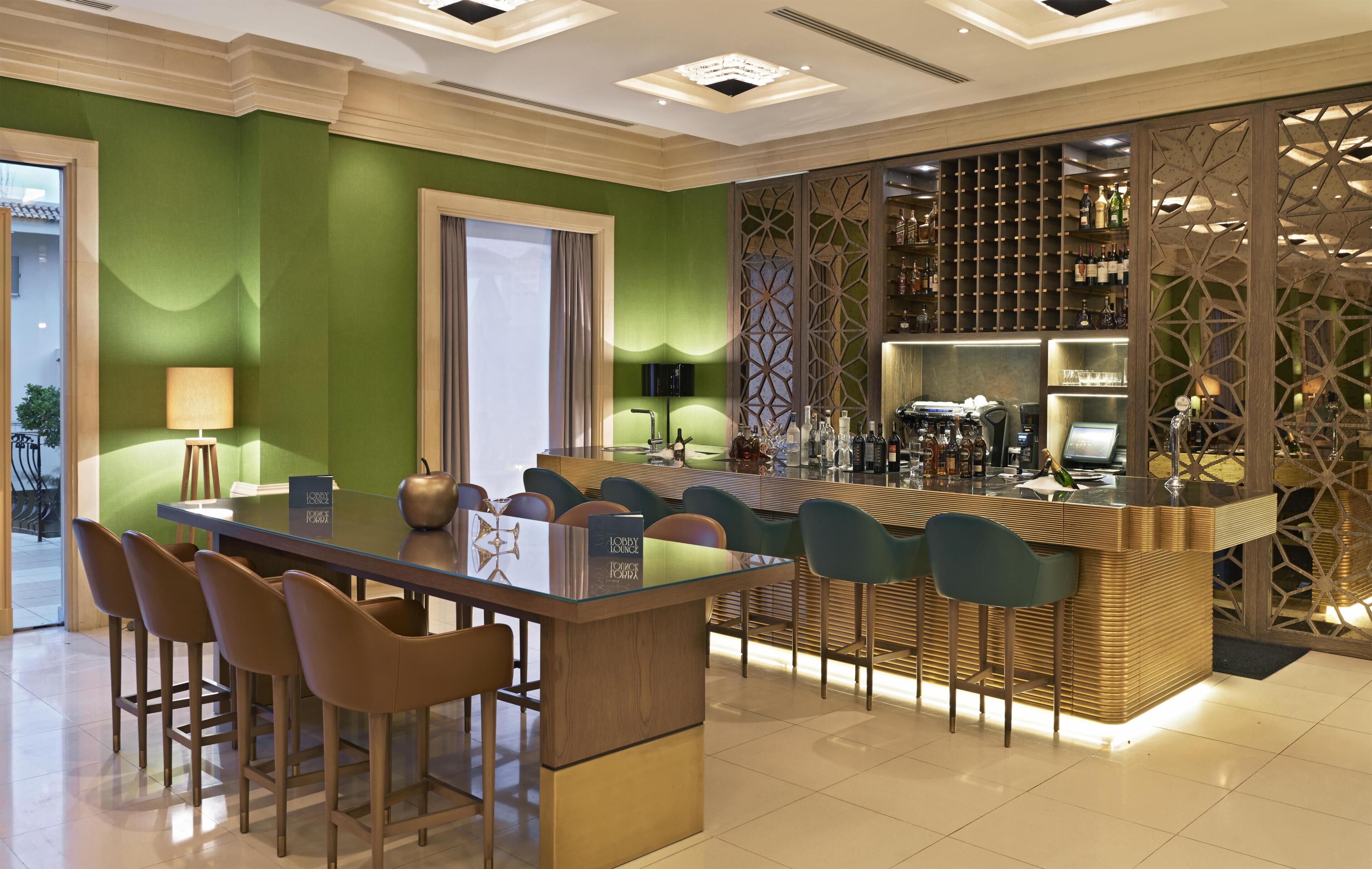 Zona bar moderna con bancone, sgabelli e scaffalatura per vino.