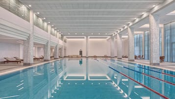 Una piscina techada, una piscina al aire libre, sombrillas